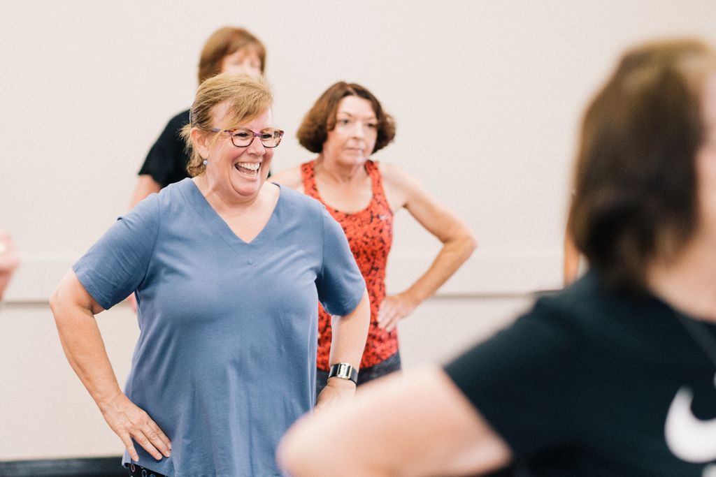 Happy middle-aged women participating in an indoor fitness class, promoting health and social interaction.